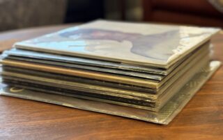 Stack of vinyl records beside a turntable in a home listening room
