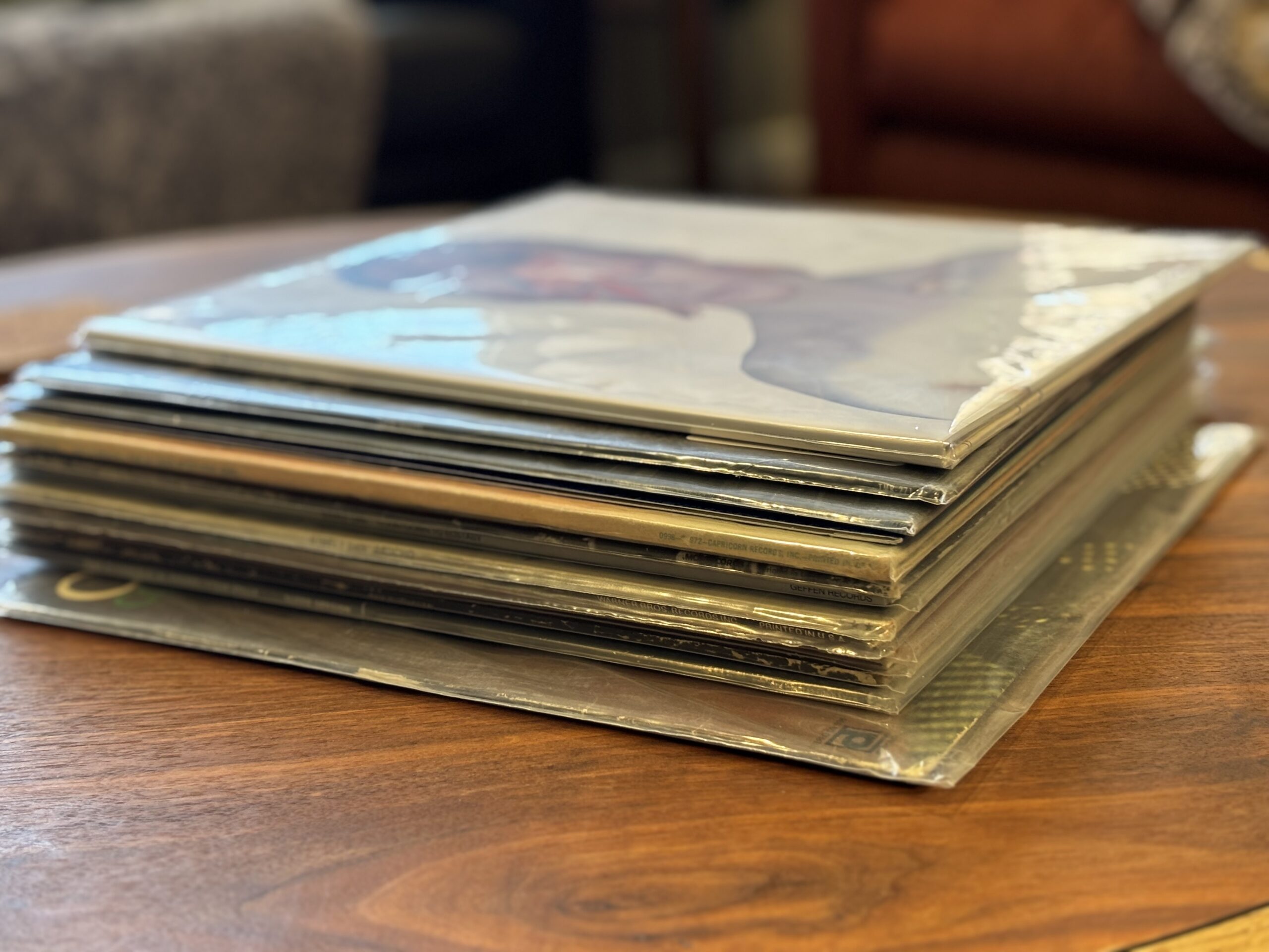 Stack of vinyl records beside a turntable in a home listening room