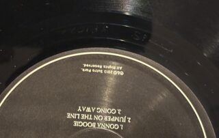 Close-up of vinyl record deadwax showing etched matrix numbers, stamps, and record label details