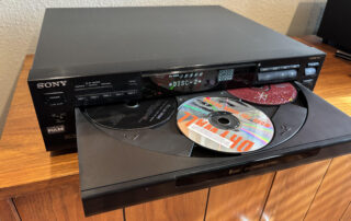 Sony 5-disc CD changer with the tray open, showing multiple CDs loaded inside a home stereo system.