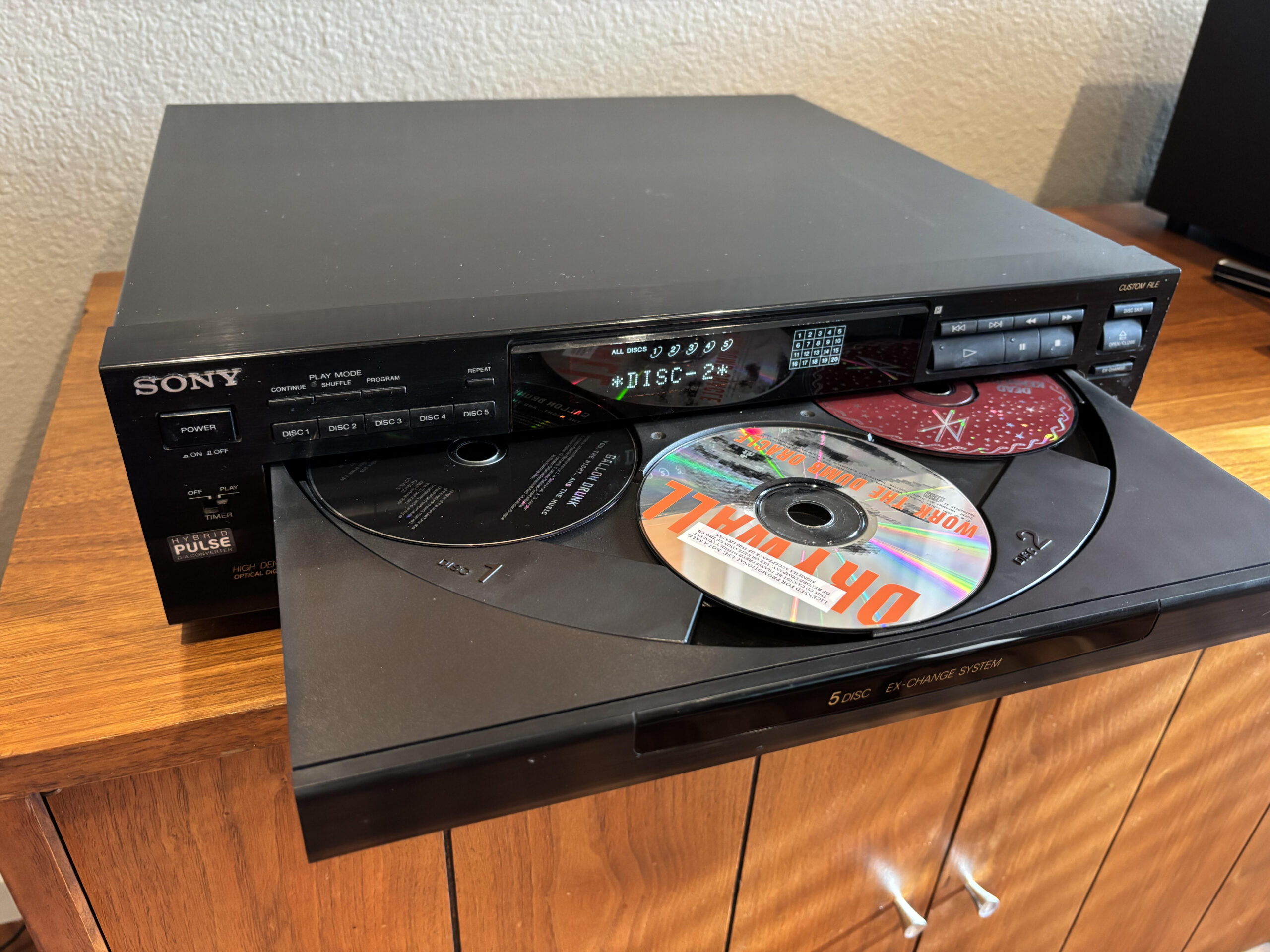 Sony 5-disc CD changer with the tray open, showing multiple CDs loaded inside a home stereo system.