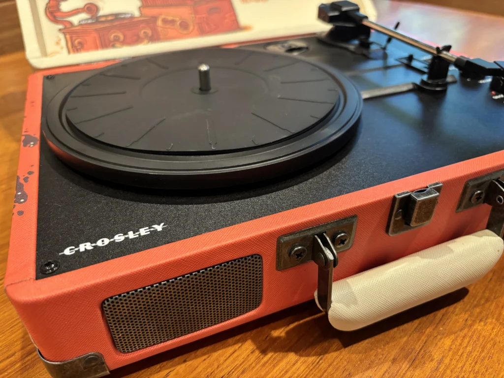 Crosley suitcase-style portable turntable spinning a vinyl record with built-in speakers and retro-inspired design.