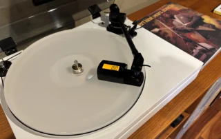 Fluance RT87 turntable tonearm being measured with a Neoteck digital stylus force gauge during cartridge setup and tracking force adjustment.