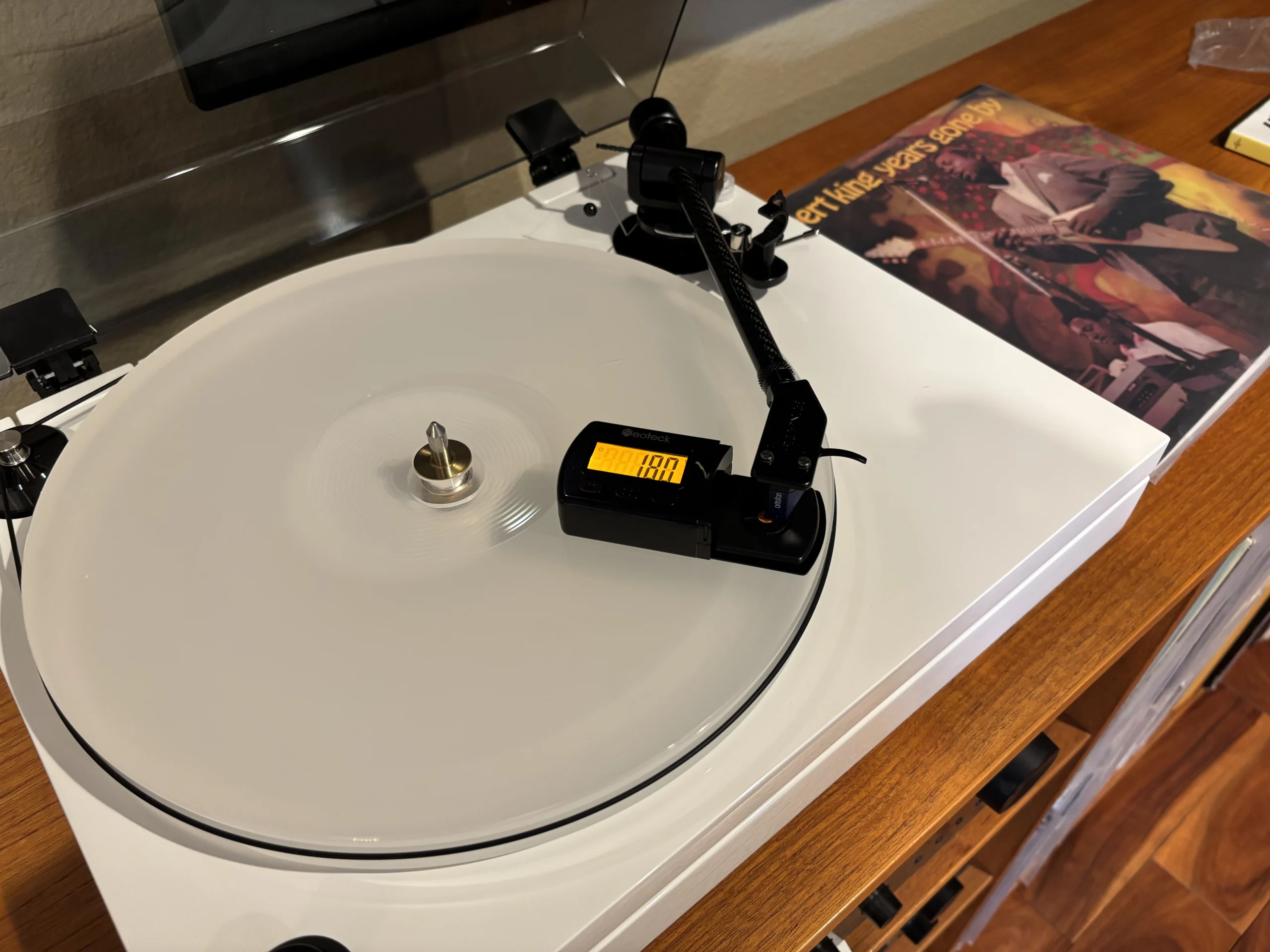 Fluance RT87 turntable tonearm being measured with a Neoteck digital stylus force gauge during cartridge setup and tracking force adjustment.