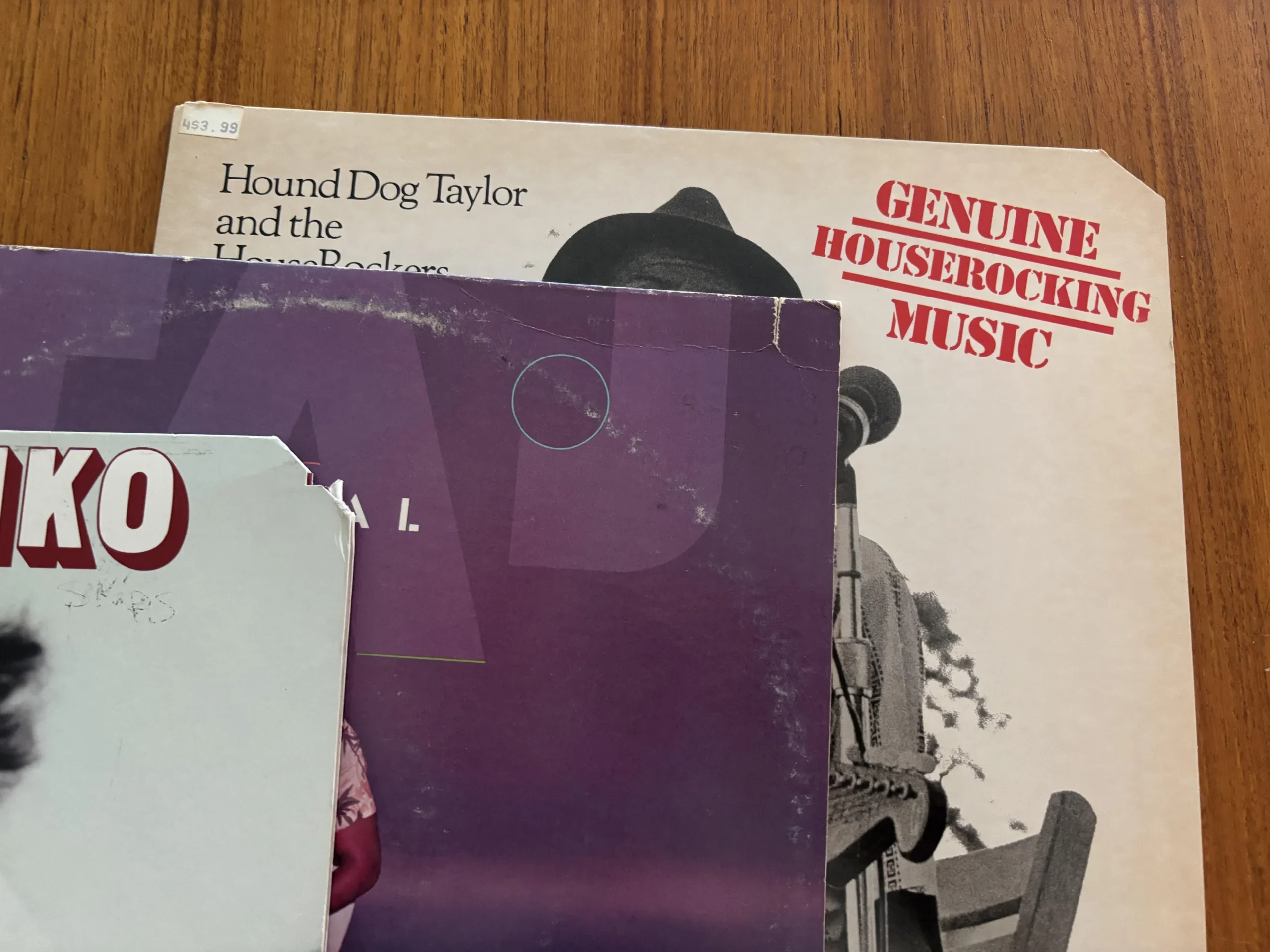 Three vinyl records showing common cutout markings, including corner cuts and a saw mark